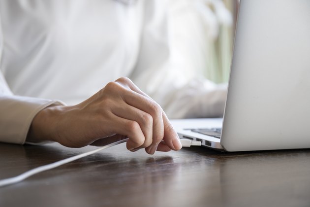Hand of a woman plugging the cord into the USB of the personal computer