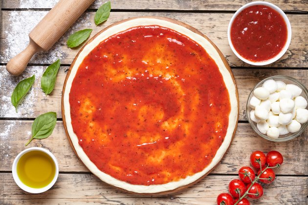 Raw dough for pizza with ingredient: tomato sauce, mozzarella, tomatoes, basil, olive oil, cheese, spices served on rustic wooden table. Flat lay. Italian pizza margarita