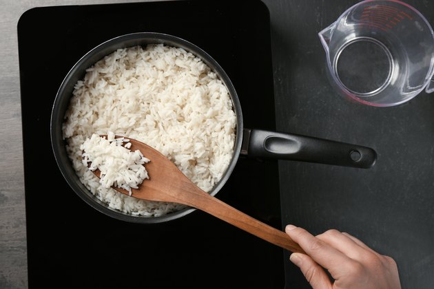 Woman cooking rice in saucepan on stove