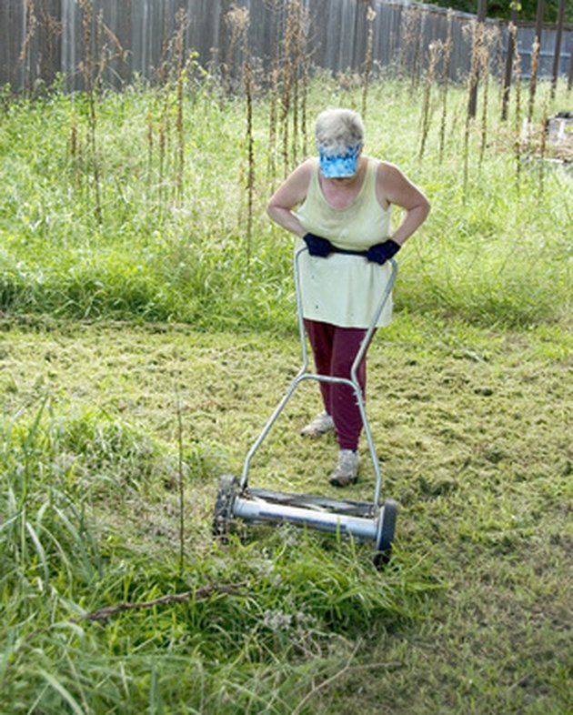 Woman trying to mow yard with manual mower