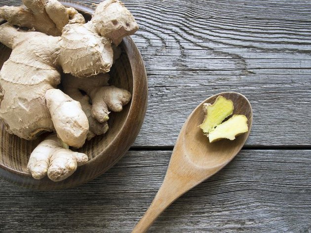 Ginger in a bowl on rustic wooden background with slice on a ladle