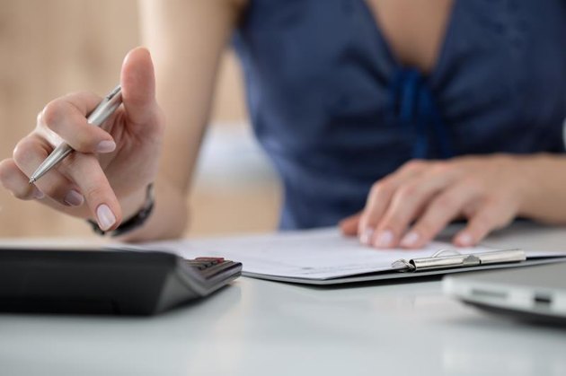 Close up of female accountant or banker making calculations. Savings, finances and economy concept