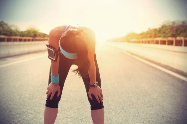 tired woman runner taking a rest after running hard on city road