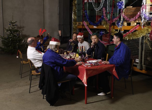 Group of workers sitting at christmas table in warehouse