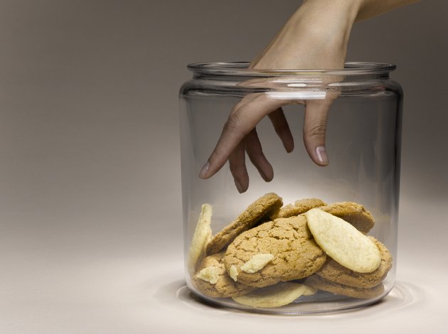 Woman reaching for cookies in cookie jar, close-up of hand