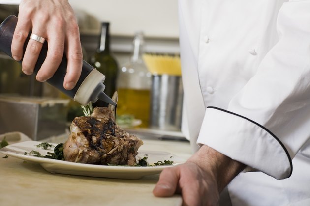 Chef drizzling garnish over pork chops