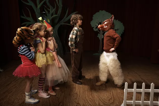 Children (5-12) acting on stage, one boy confronting bad wolf