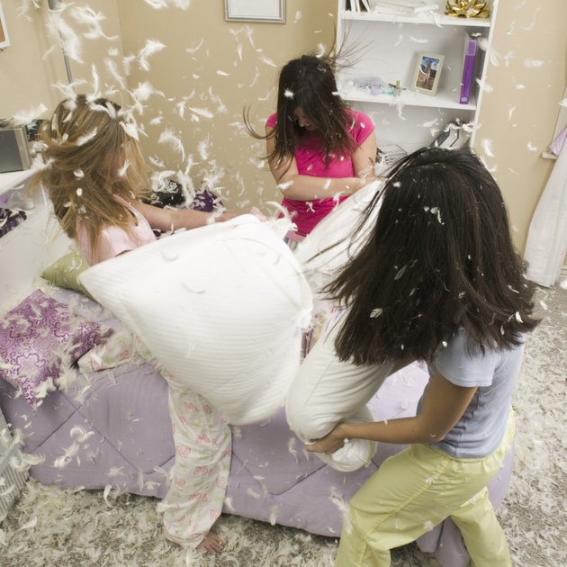 High angle view of three teenage girls having a pillow fight