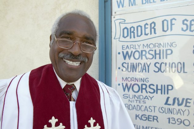 Portrait of a Smiling Priest Standing by a Notice Board