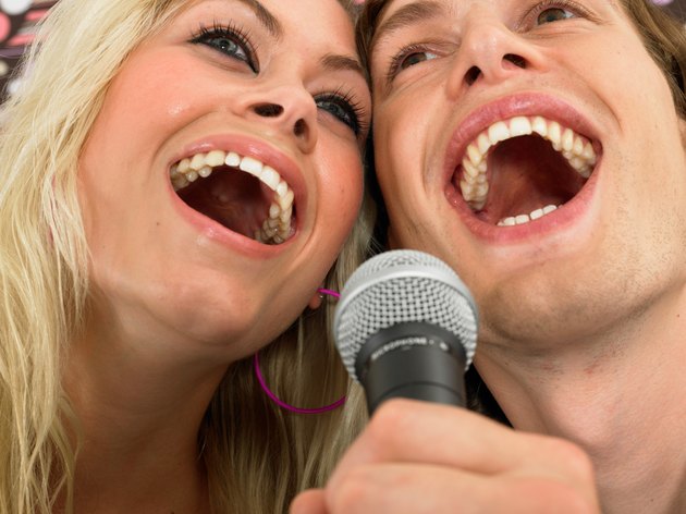 Young woman and man singing into microphone, close-up, low angle view