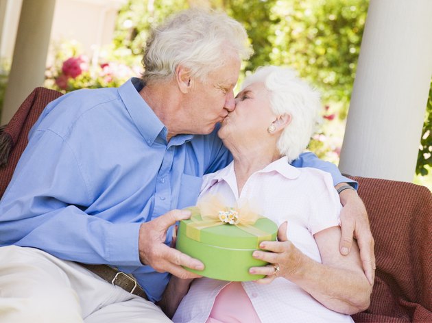 Husband giving wife gift on patio and kissing her