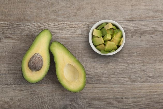 Top view of half and white bowl full of diced avocado