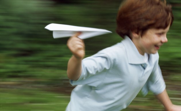 Boy (10-11) playing with a paper plane