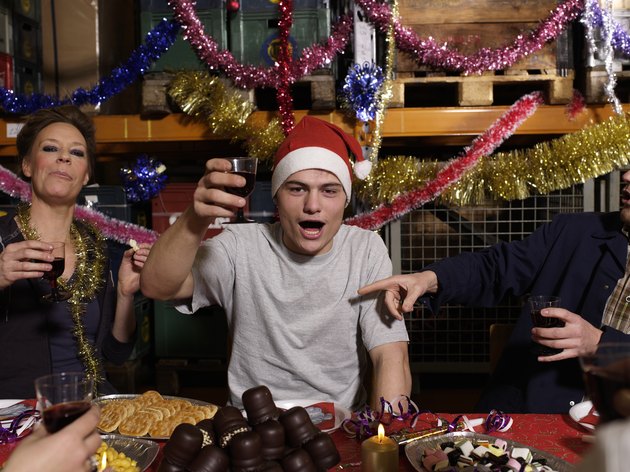 Group of workers toasting with wine glasses at Christmas table in warehouse, portrait