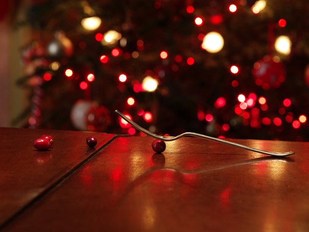Fork balanced on cranberry in front of Christmas tree