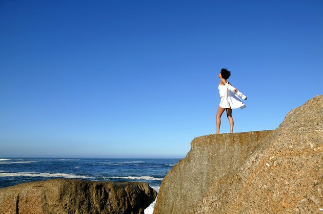 Woman standing on cliff by seashore