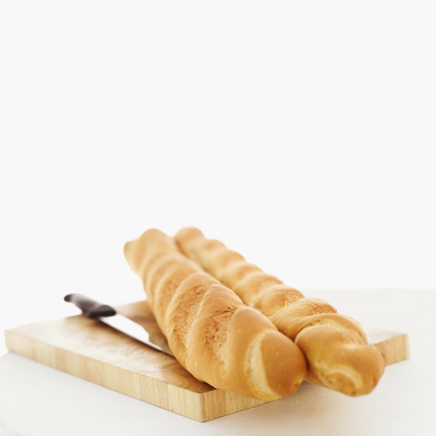 Close-up of baguette halved with a knife on a cutting board