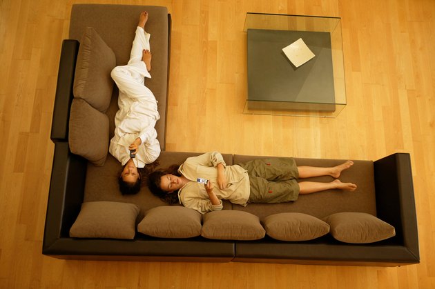 Young women lounging on sofa with cell phones