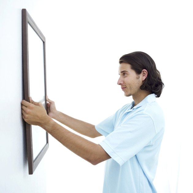 young man fixing a picture frame on the wall