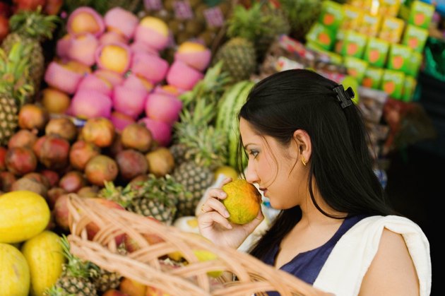Side profile of a young woman smelling a fruit