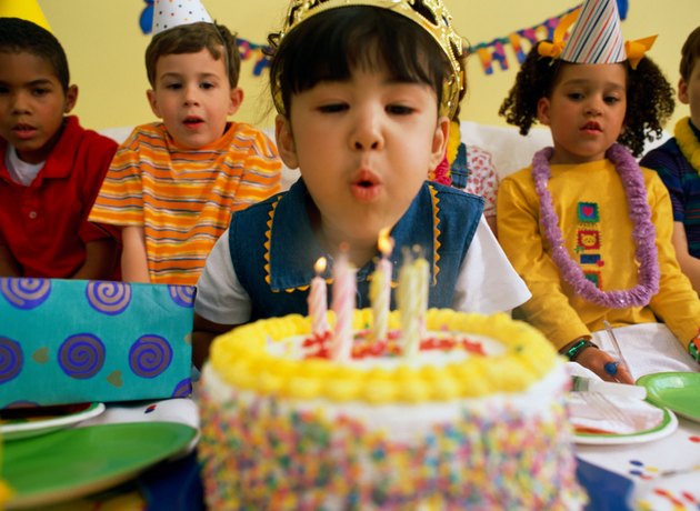 Girl (5-7) blowing out birthday candles