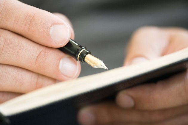 Close-up of man writing with fountain pen