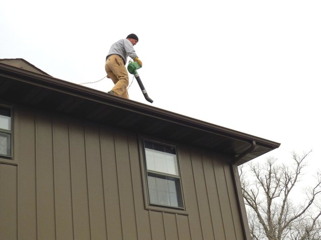 Homeowner Cleaning Eaves Using a Leaf Blower