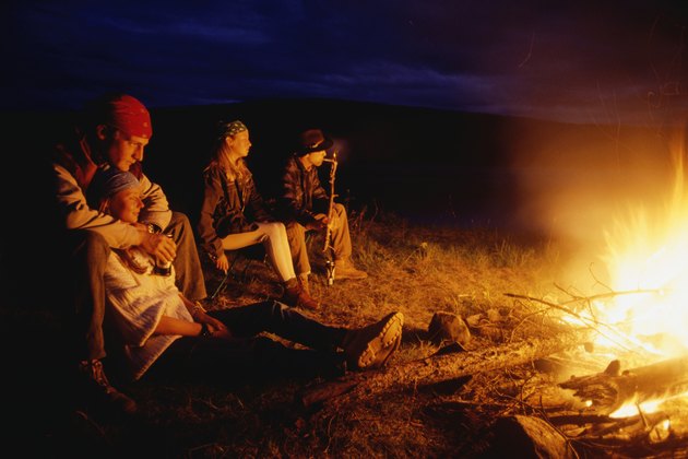 Four people sitting by open fire at night