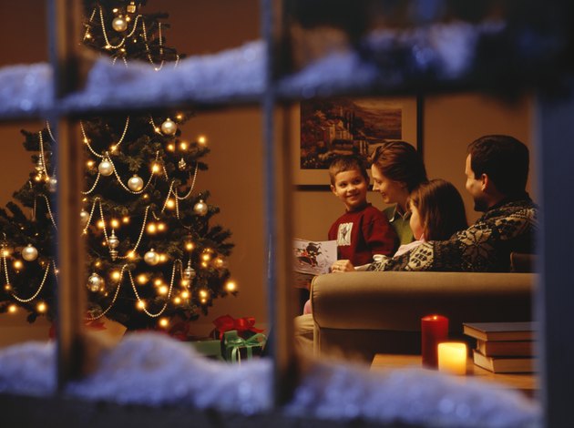 Family reading together on sofa at Christmas time, viewed through window