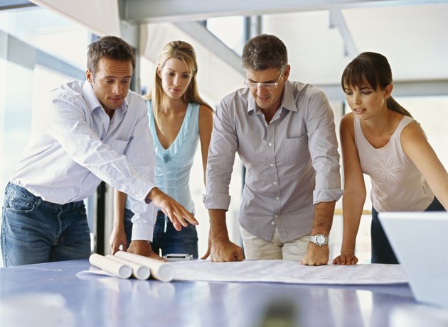 group of business executives looking at a blueprint in an office