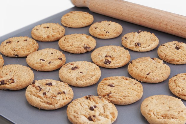 Chocolate chip cookies on a baking tray with a rolling pin