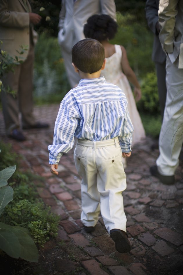 Girl and boy (4-5) running in garden, rear view, others in background