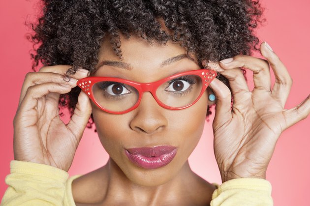 Portrait of an African American woman wearing retro style glasses over colored background