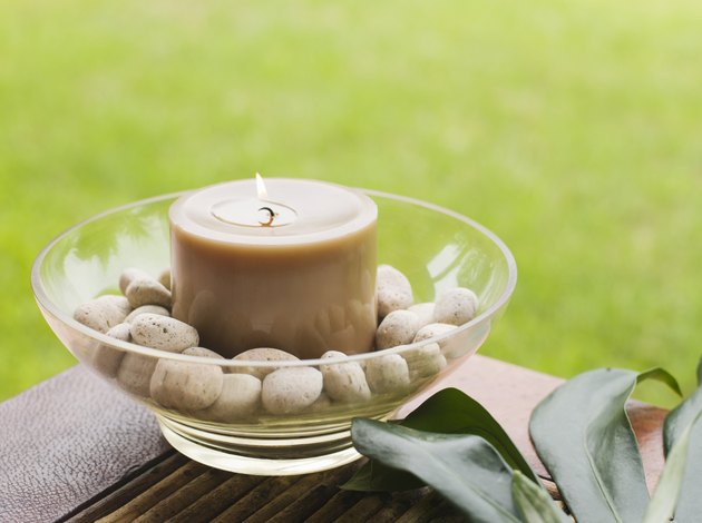 Bowl with candle and pebbles on table outdoors