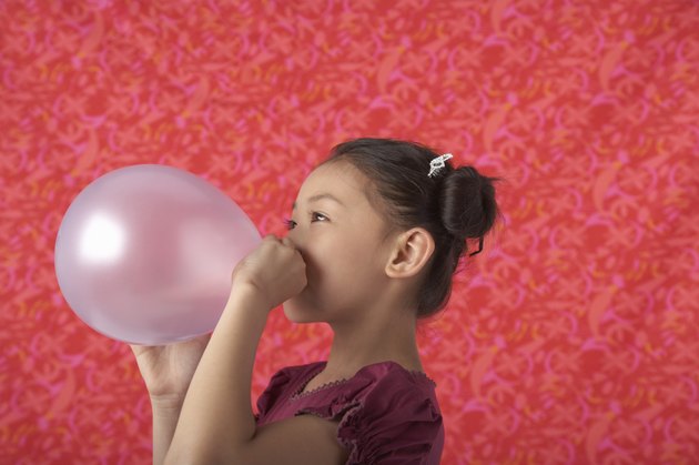 Girl (5-7) blowing balloon