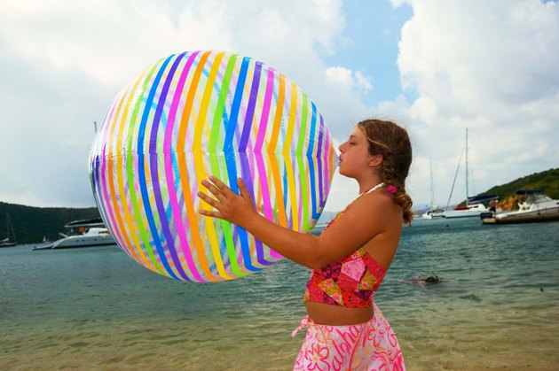 Teenage girl blowing up beach ball