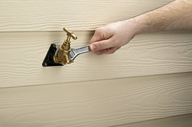 Hand holding adjustable wrench to tighten locking nut on outside tap