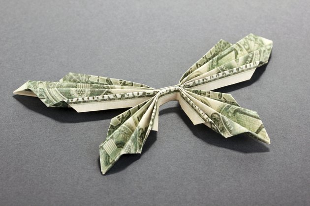 Dollar folded into butterfly on grey background