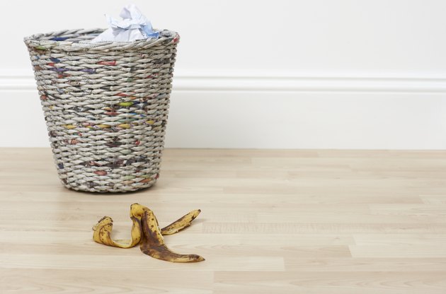 banana skin on the floor next to a bin
