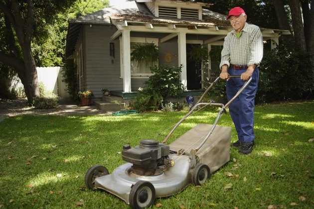 Portrait of elderly man mowing lawn