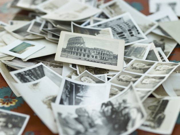 Various black and white photographs in pile on table