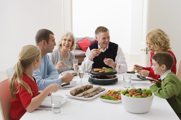 Family cooking vegetables on raclette grill