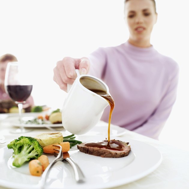 woman pouring gravy over a piece of sliced meatloaf