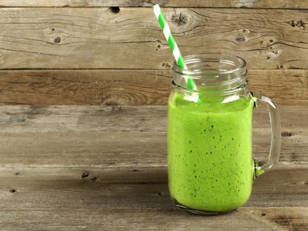 Healthy green smoothie in a mason jar mug on old wood