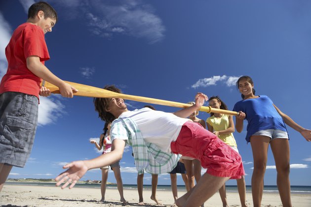 Teenagers doing limbo dance on beach