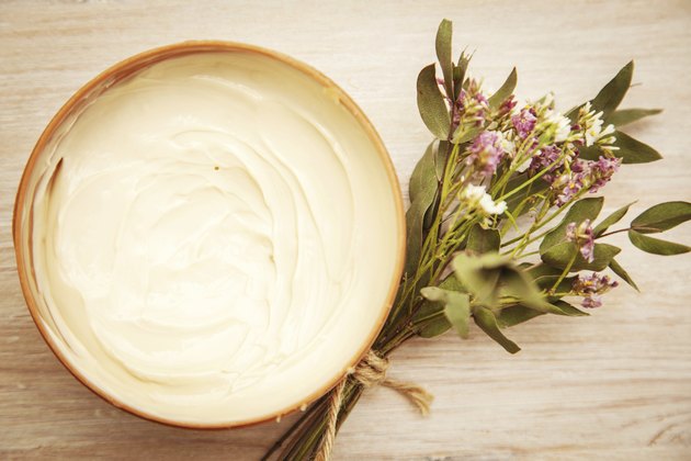 body cream and wildflowers on wooden table