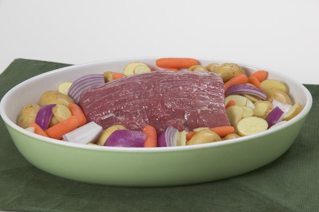 Uncooked pot roast on a bed of vegetables