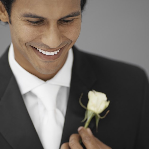 close-up of a groom holding a white rose
