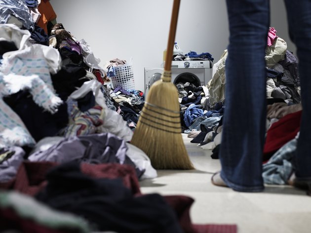 Woman sweeping pathway through piles of laundry