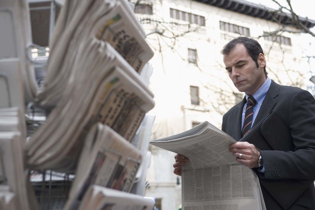 Businessman with newspaper at newsstand